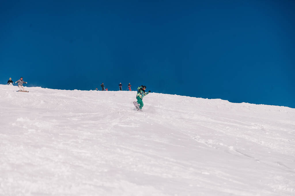 Karpaty, Ukraine, February 8, 2023. Skiers and snowboarders freeride in clear sunny weather on the slopes of the mountains near the resort of Dragobrat. High quality photo - Valokuva, kuva