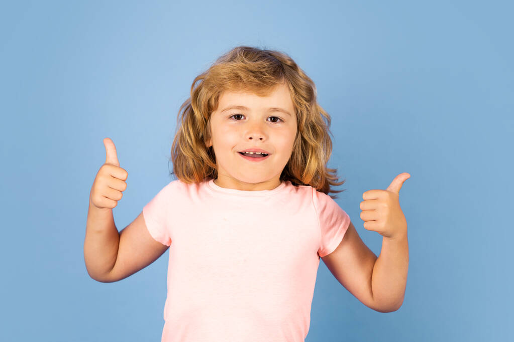 Child showing thumbs up on studio isolated background. Portrait of kid boy making thumbs up sign - Foto, Imagem