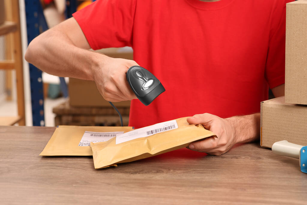 Employé de bureau de poste avec scanner lisant le code à barres du colis au comptoir, gros plan - Photo, image