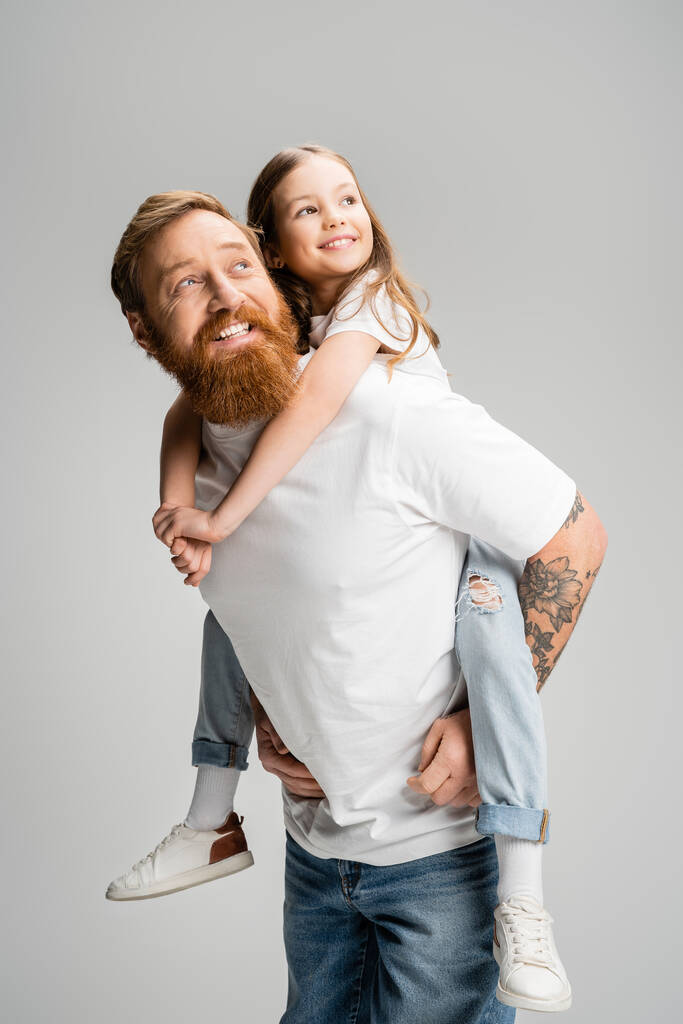 Uśmiechnięty ojciec trzyma nastoletnią córkę i odwraca wzrok na szarym  - Zdjęcie, obraz