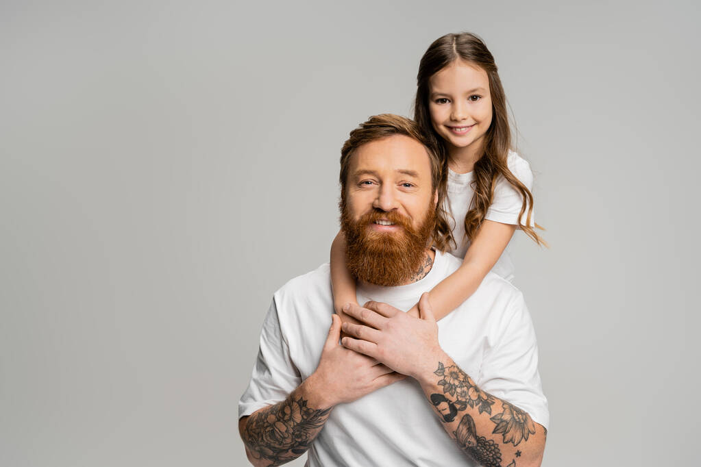 Carefree dívka objímání šťastný a tetovaný rodič v tričku izolované na šedé  - Fotografie, Obrázek