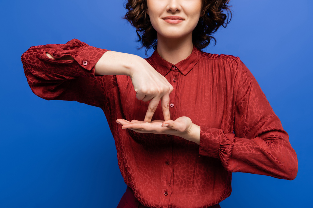 partial view of positive teacher showing gesture meaning stand on sign language isolated on blue - Photo, Image