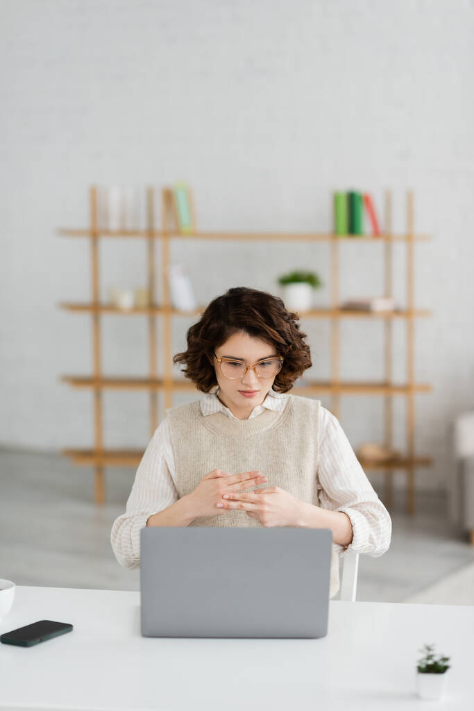 junge Frau mit Brille zeigt Namenswort in Gebärdensprache während Online-Unterricht am Laptop zu Hause - Foto, Bild