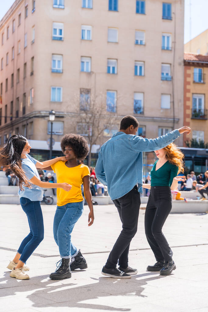 Jeunes amis multi-ethniques dansant sur une place de la ville, groupe d'amis divers s'amusant - Photo, image