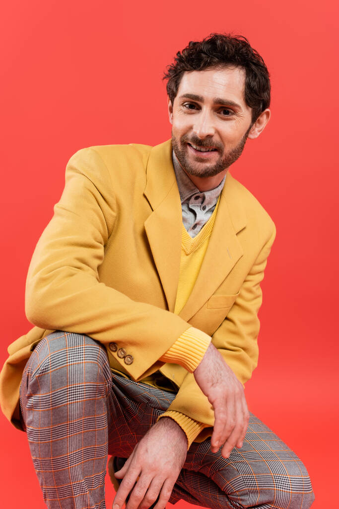 Portrait of overjoyed man in stylish yellow jacket posing isolated on coral red  - Photo, Image