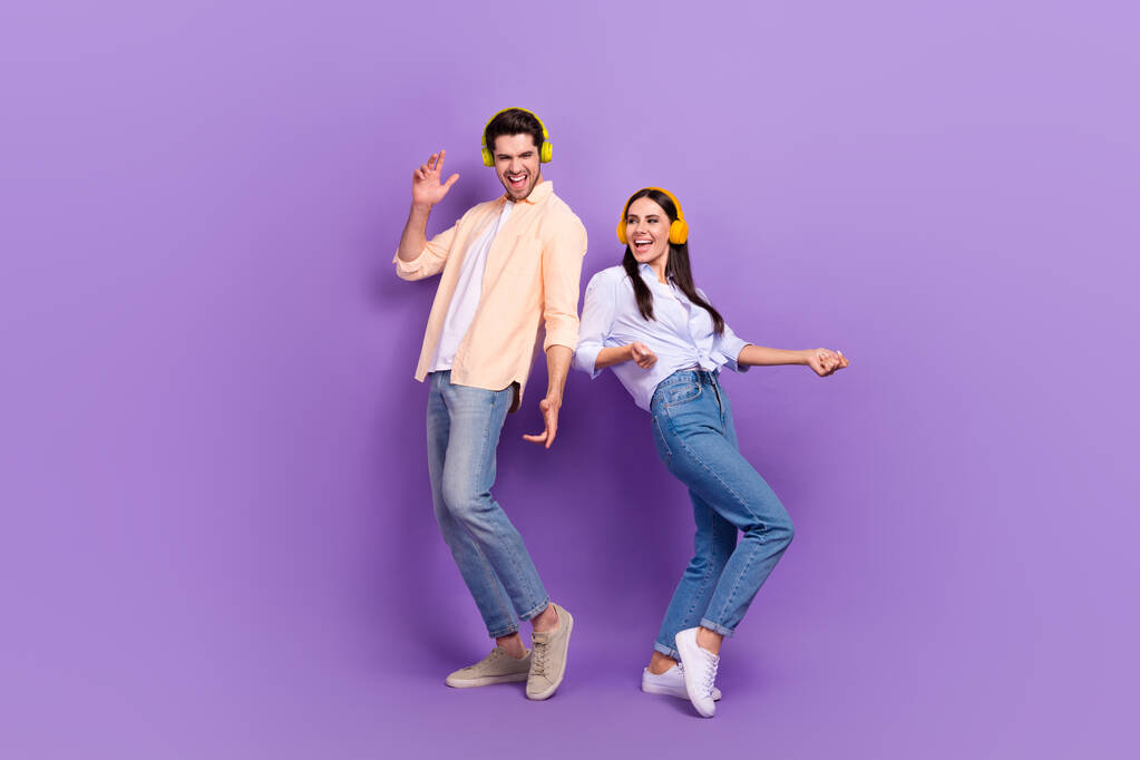 Портрет двох веселих безтурботних людей, які танцюють, мають гарний настрій ізольовано на фіолетовому кольоровому фоні
. - Фото, зображення