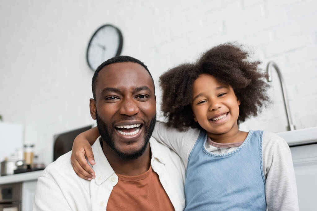 Porträt eines freudigen afrikanisch-amerikanischen Vaters und eines glücklichen Kindes, das in die Kamera blickt  - Foto, Bild