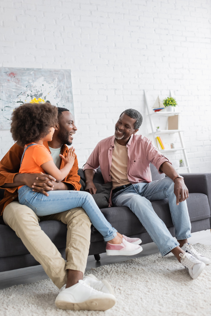 Joyeux père et enfant afro-américain parlant à grand-parent sur le canapé à la maison  - Photo, image