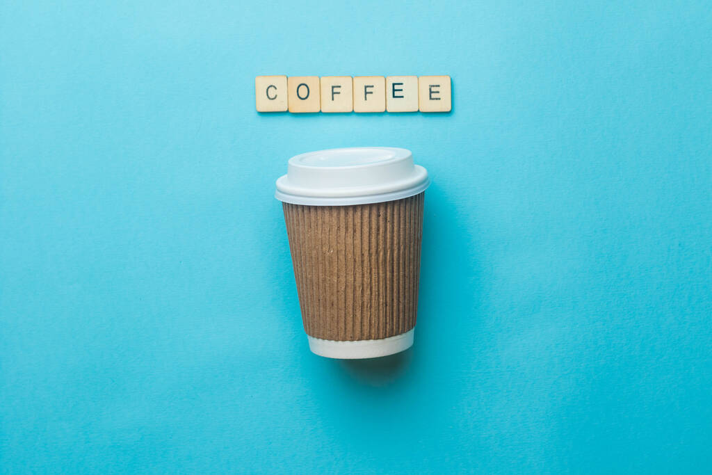 Kaffeetasse und Deckel aus Papier mit einem Schild mit der Aufschrift Kaffee auf blauem Hintergrund - Foto, Bild