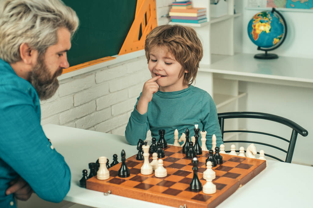 Un bel bambino che gioca a scacchi con il padre. Un bell'insegnante che dà lezioni private di scacchi al ragazzo dell'asilo. Torniamo a scuola. Buon padre e figlio
 - Foto, immagini