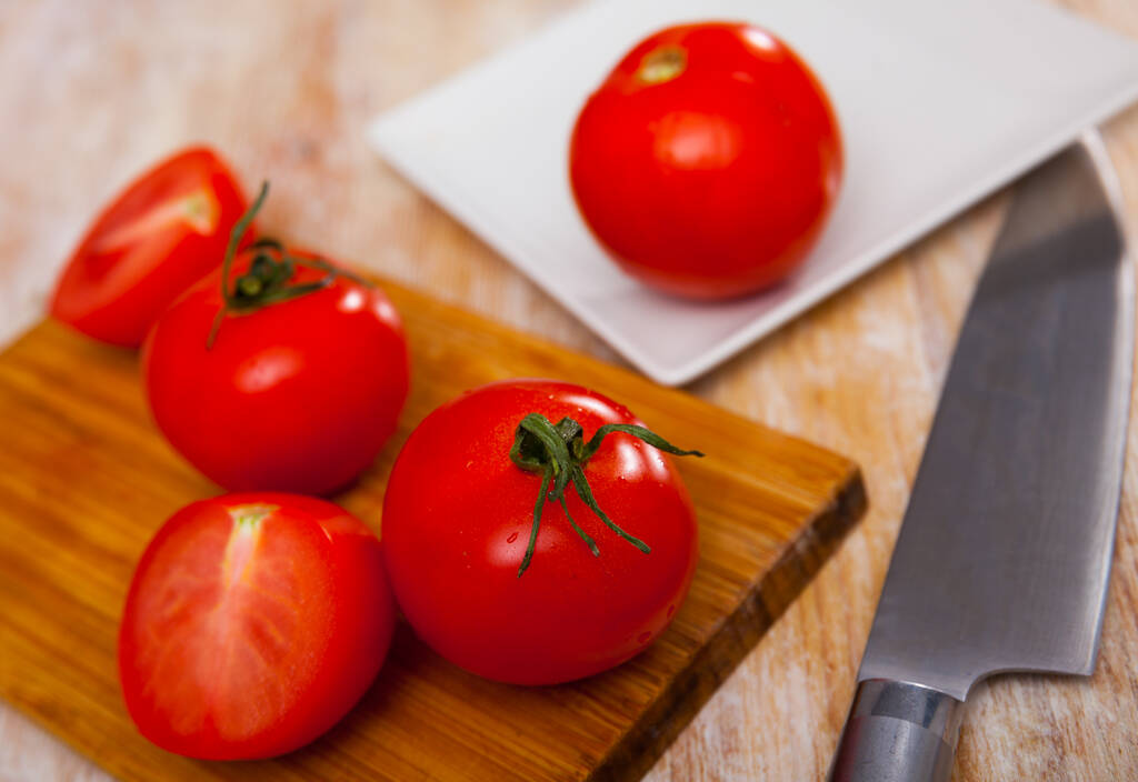 Свіжі червоні помідори на дерев'яній обробній дошці з кухонним ножем
. - Фото, зображення