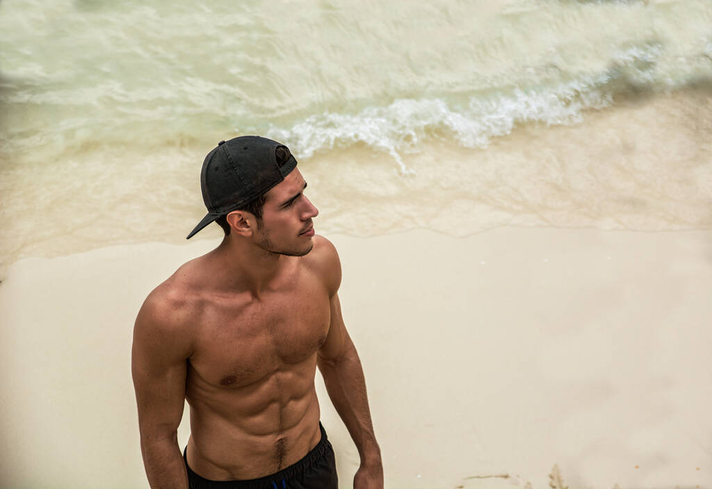 Metade do corpo de um jovem bonito em pé em uma praia em Phuket Island, Tailândia, sem camisa vestindo shorts boxer, mostrando corpo musculoso em forma - Foto, Imagem