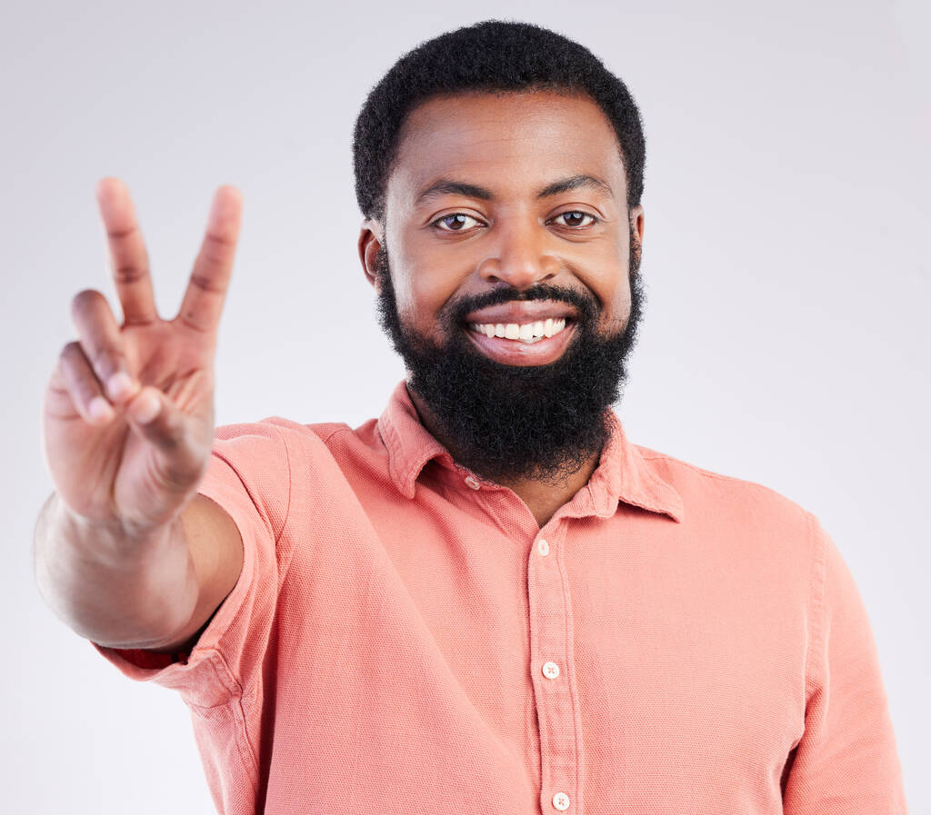 Black man, hand and peace sign in studio portrait with smile, emoji or happiness by background. Young african model, signal or zen symbol for opinion, mindset or voice for confident pride by backdrop. - Photo, Image