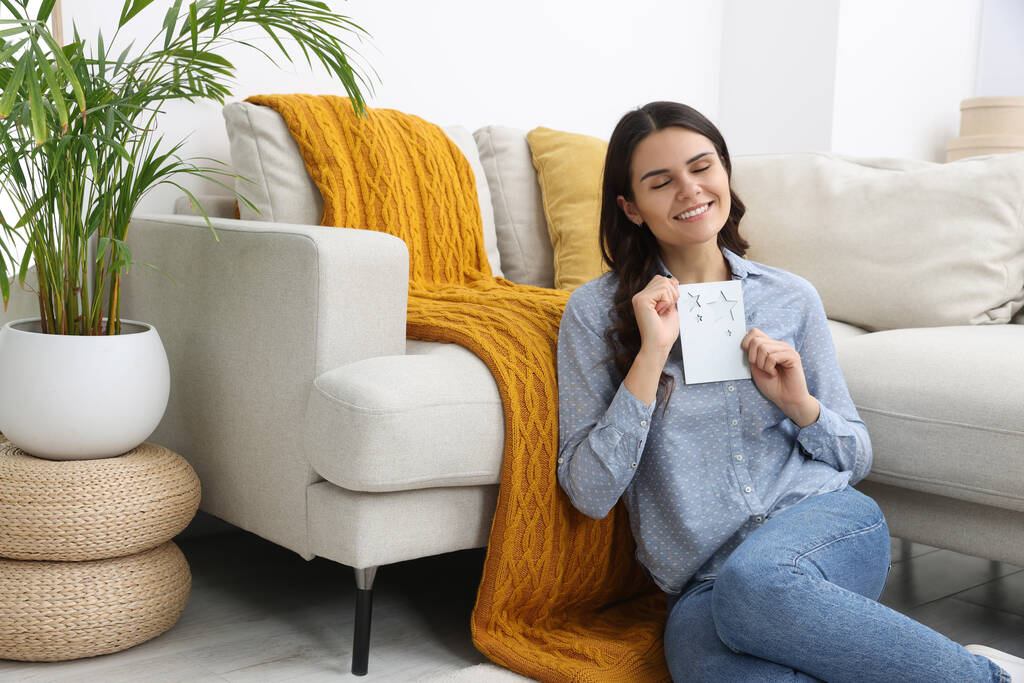 Fiatal nő üdvözlőkártyával a padlón a nappaliban - Fotó, kép