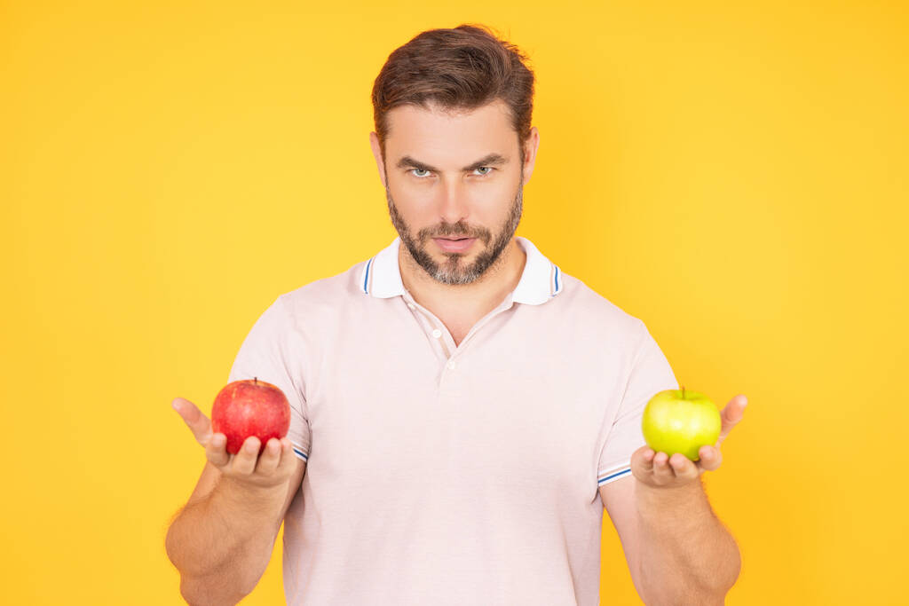 Beißender Apfel. Porträt eines jungen Mannes, der isoliert vor gelbem Hintergrund Apfel isst. Gesundes Apfelobst für natürliche Vitamine, Diäten und Veganer. Studioporträt eines hispanischen Typen, der Apfel isst - Foto, Bild