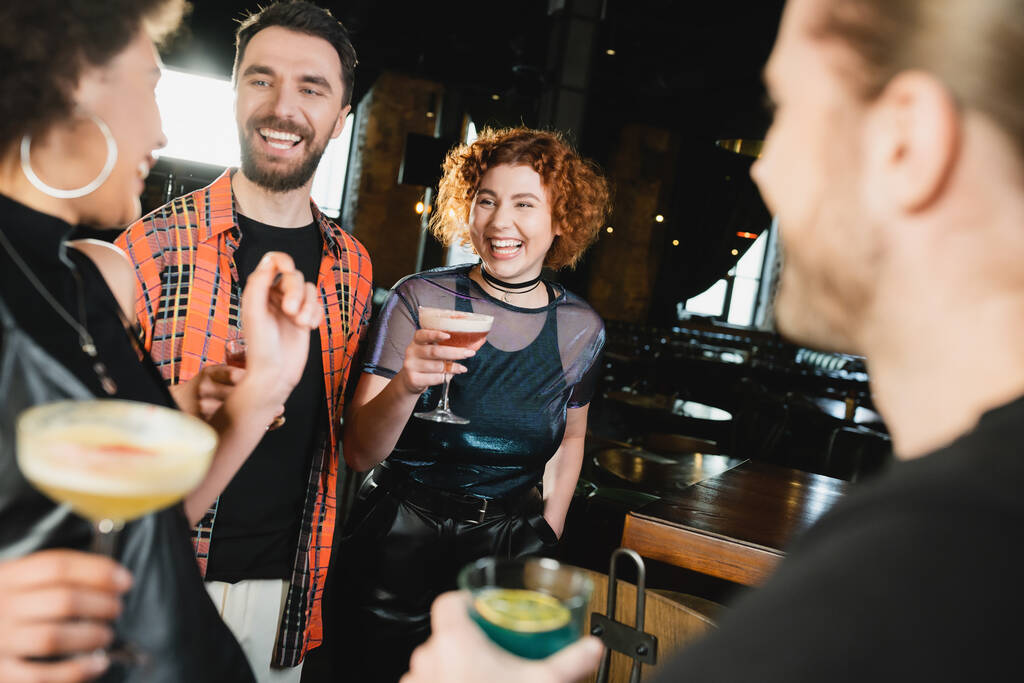 Позитивні багатоетнічні друзі з різними коктейлями зустрічаються в барі вночі
  - Фото, зображення