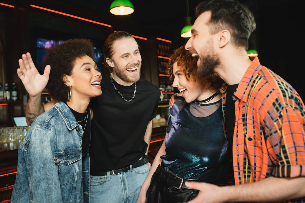 Felices amigos multiétnicos hablando mientras pasan tiempo en el bar  - Foto, imagen