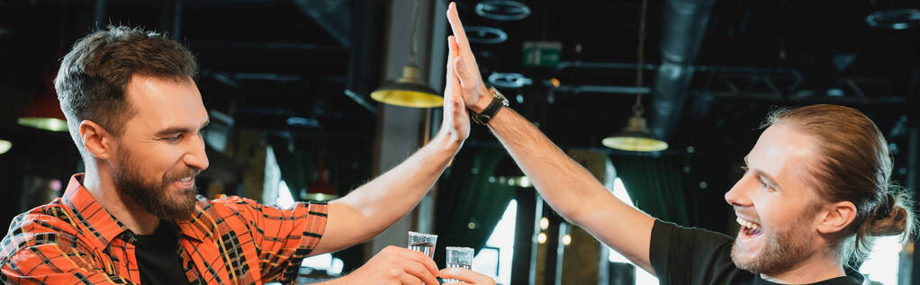 Χαρούμενα γενειοφόροι άνδρες κρατώντας τεκίλα και δίνοντας κόλλα πέντε στο μπαρ, πανό  - Φωτογραφία, εικόνα