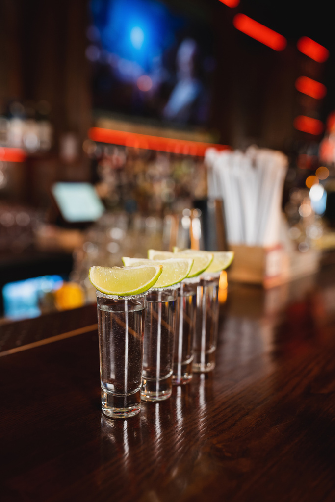 Tequila shots avec citron vert frais sur support de bar en bois  - Photo, image
