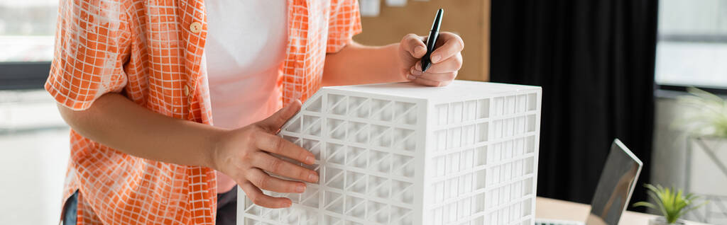 cropped view of architectural designer holding stylus pen near residential house model in office, banner  - Photo, Image