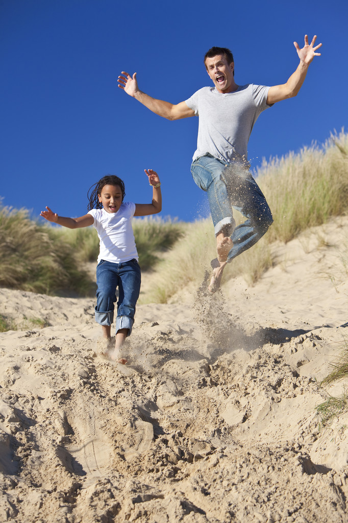 man & meisje, gelukkig vader en dochter springen op strand - Foto, afbeelding