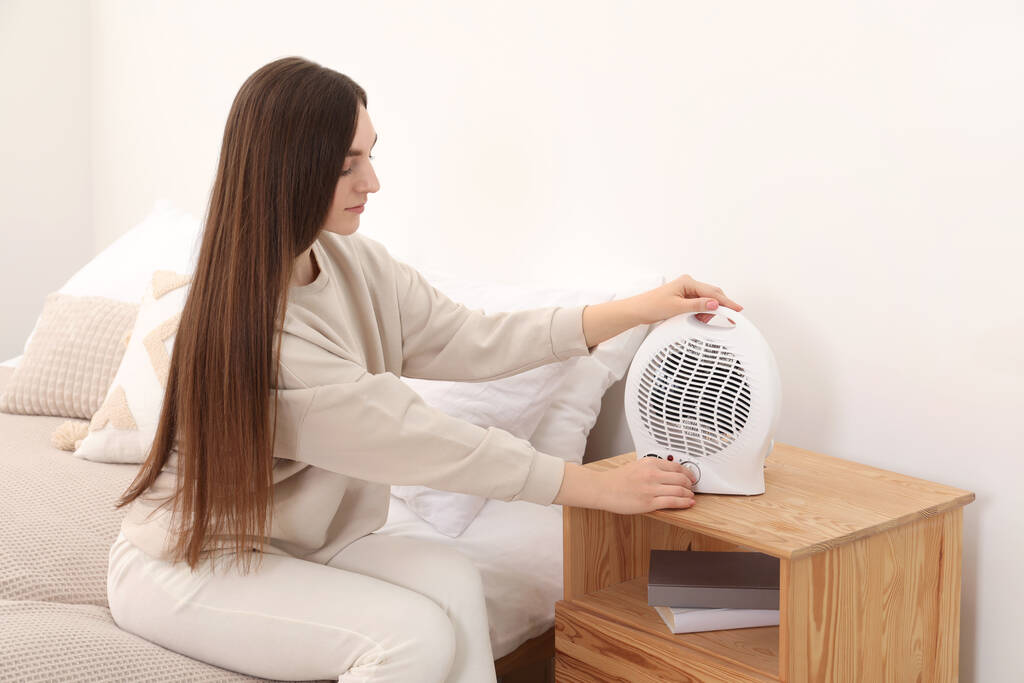 Nő bekapcsolása modern elektromos ventilátor fűtés otthon - Fotó, kép