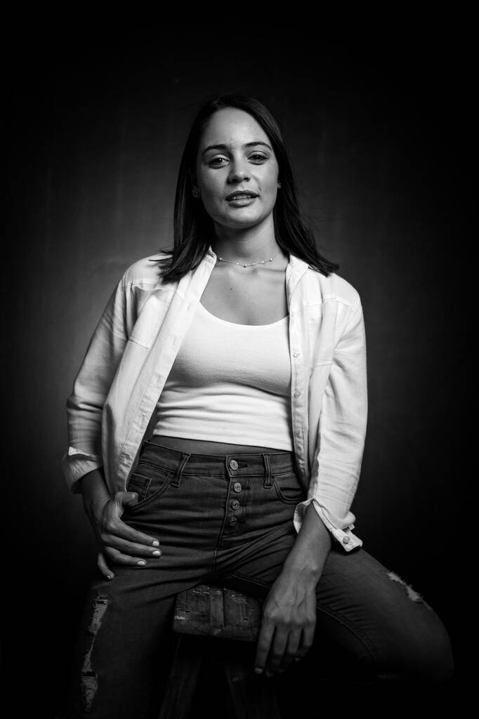 Jolie fille brune posant pour un tournage de mode dans un studio. Elle est vêtue d'un jean élégant et d'un haut de culture, et ses poses véhiculent un sentiment de jeunesse et de vitalité. - Photo, image
