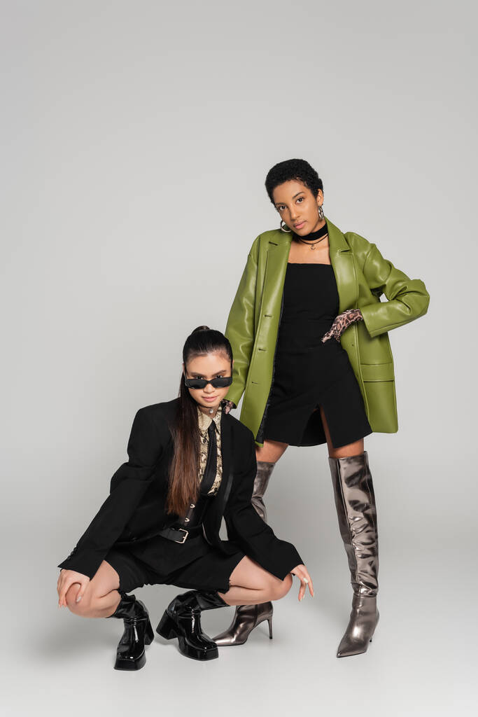 Fiatal multietnikus barátnők divatos ruhák pózol szürke háttér - Fotó, kép