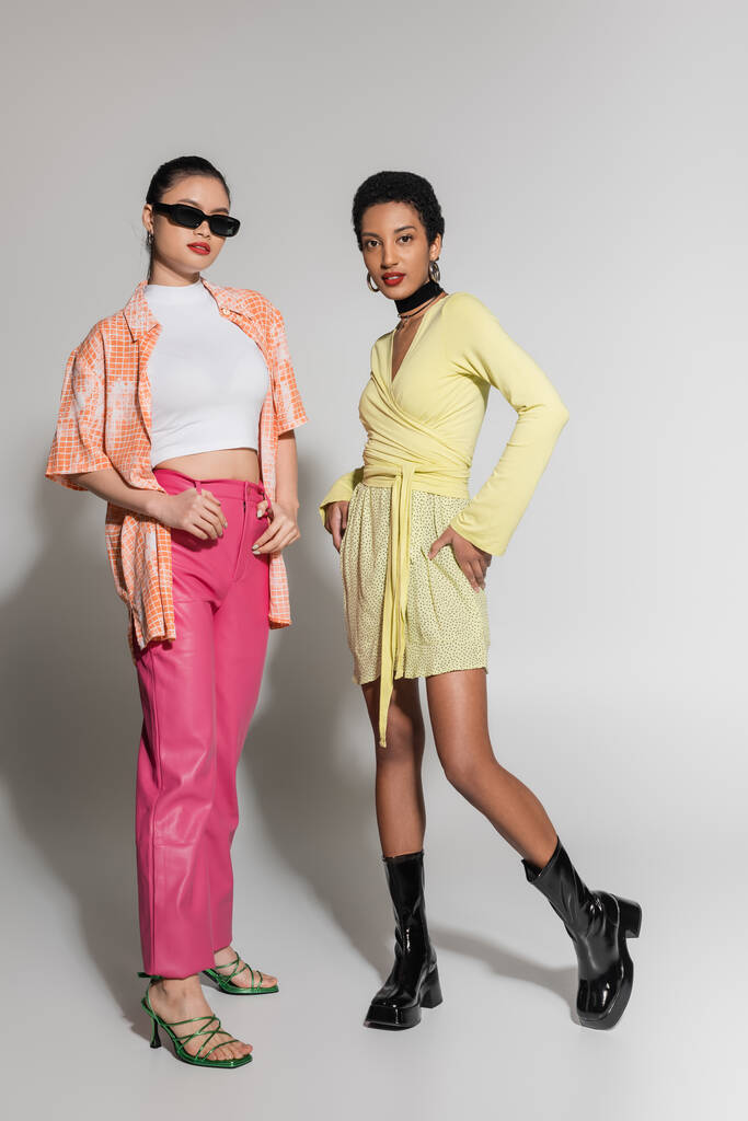 Modelos interraciales en ropa de primavera colorida posando sobre fondo gris  - Foto, Imagen