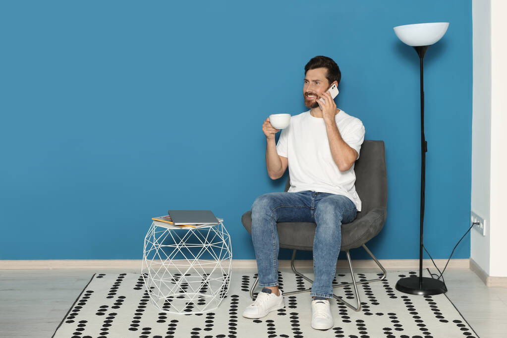 Muž mluví na chytrém telefonu v křesle, prostor pro textovky. Stylový interiér pokoje - Fotografie, Obrázek