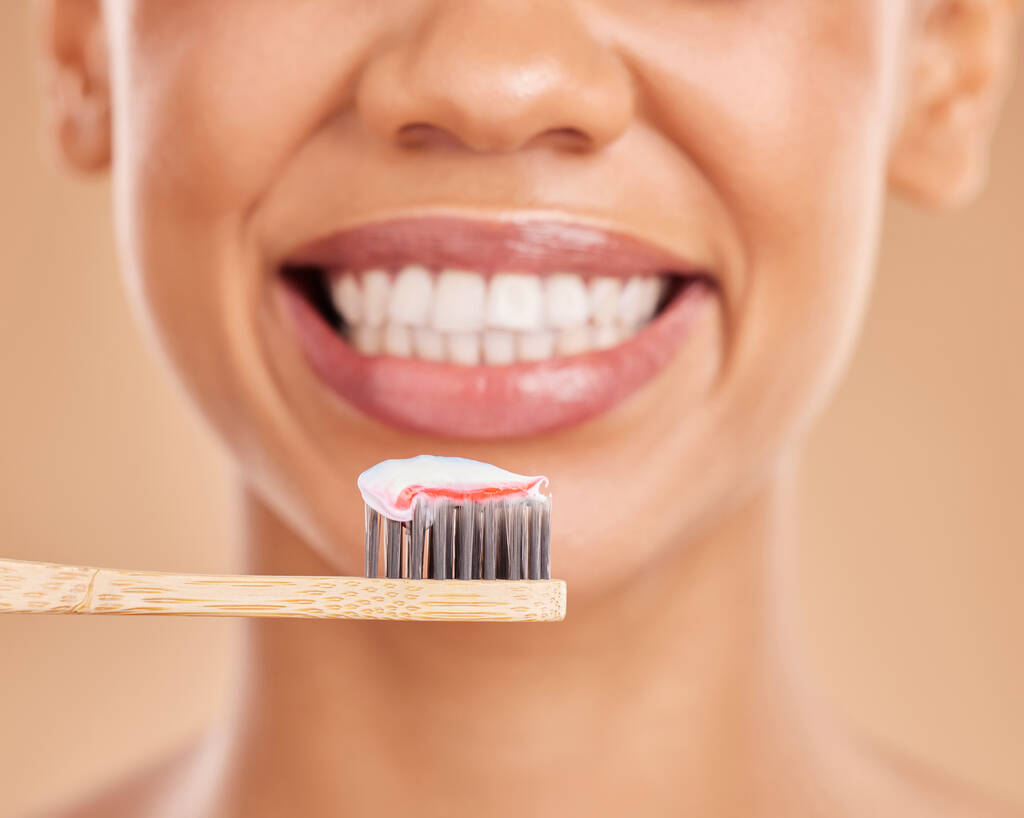 Frau, Zähne und breites Lächeln mit Zahnbürste für Zahnpflege, Hygiene oder Wellness vor Studiohintergrund. Nahaufnahme eines lächelnden weiblichen Mundes mit Zahnpasta für gesunde oder saubere Mund- und Zahnfleischbehandlungen. - Foto, Bild