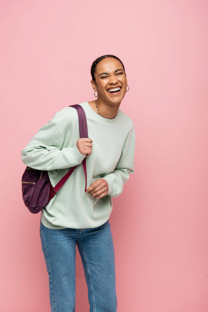 Estudante afro-americano animado com mochila de pé isolado em rosa  - Foto, Imagem