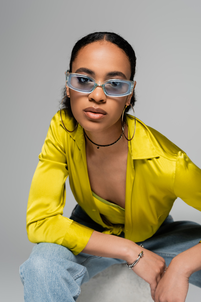 portré fiatal afro-amerikai modell stílusos napszemüveg nézi kamera elszigetelt szürke  - Fotó, kép