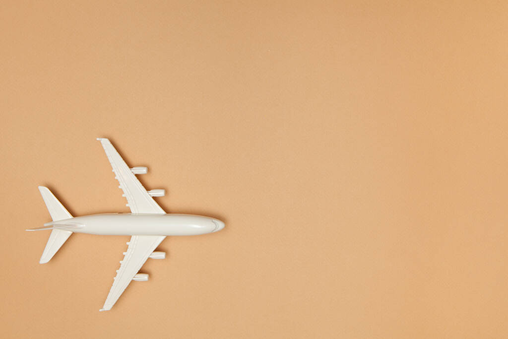 飛行機モデル。茶色の背景に白い飛行機。旅行休暇のコンセプト。夏の背景。フラットレイアウト、トップビュー、コピースペース. - 写真・画像