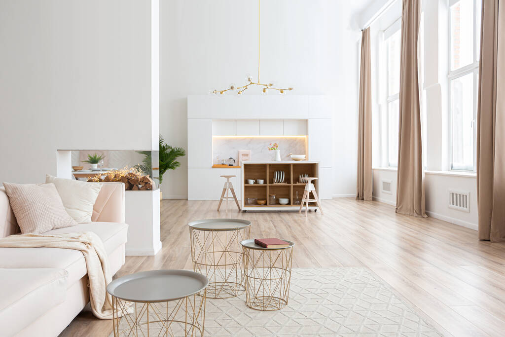 interieur ontwerp ruime lichte studio appartement in Scandinavische stijl en warme pastel wit en beige kleuren. trendy meubels in de woonkamer en moderne details in de keuken. - Foto, afbeelding