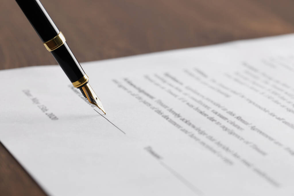 Schrijven op document met vulpen aan houten tafel, close-up. Notariële overeenkomst - Foto, afbeelding