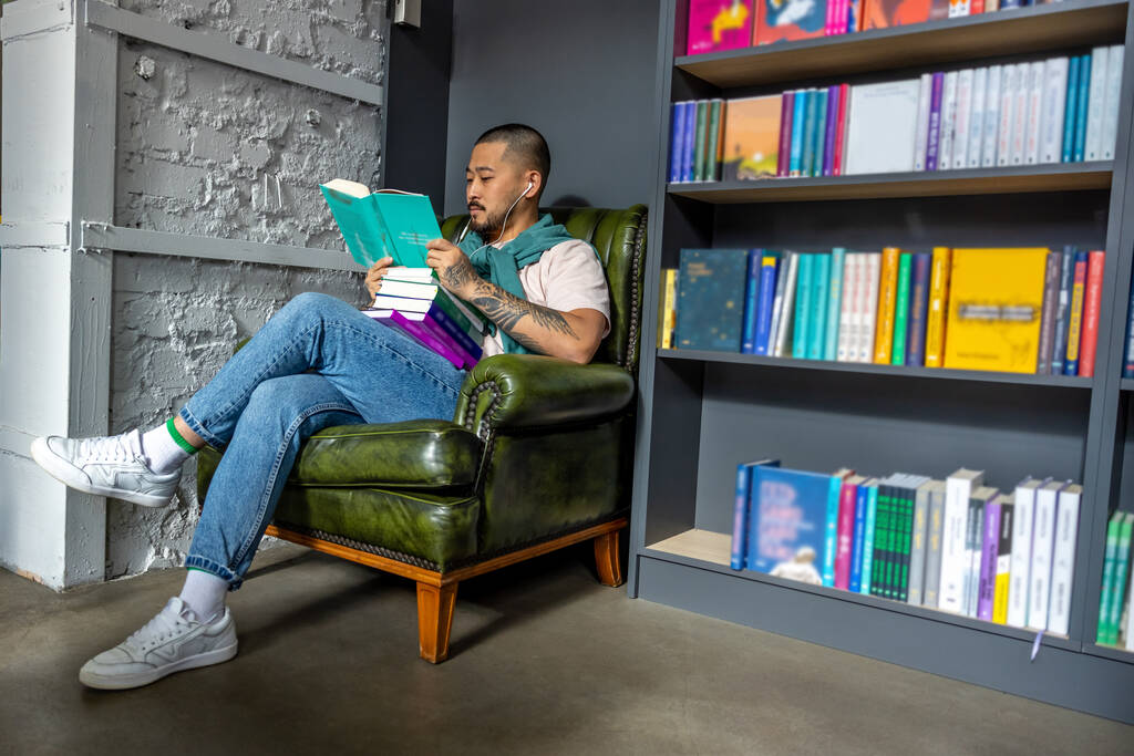 In biblioteca. Giovane asiatico uomo seduta con un libro in biblioteca - Foto, immagini