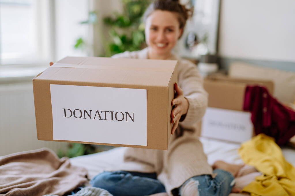 Mladá žena dává své oblečení zabalené v krabici na charitu. - Fotografie, Obrázek