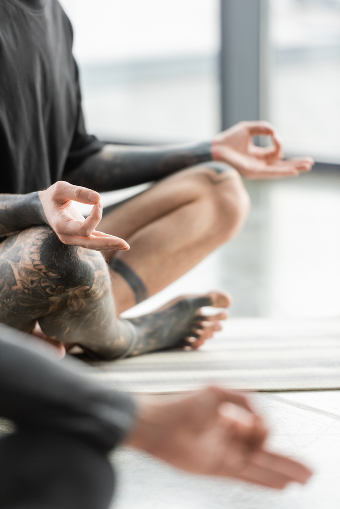Vista cortada do homem tatuado praticando mudra gyan na aula de ioga  - Foto, Imagem