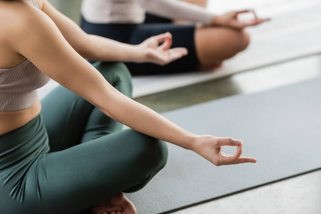Gewassen beeld van vrouw in sportkleding praktiserend gyan mudra in yoga studio   - Foto, afbeelding
