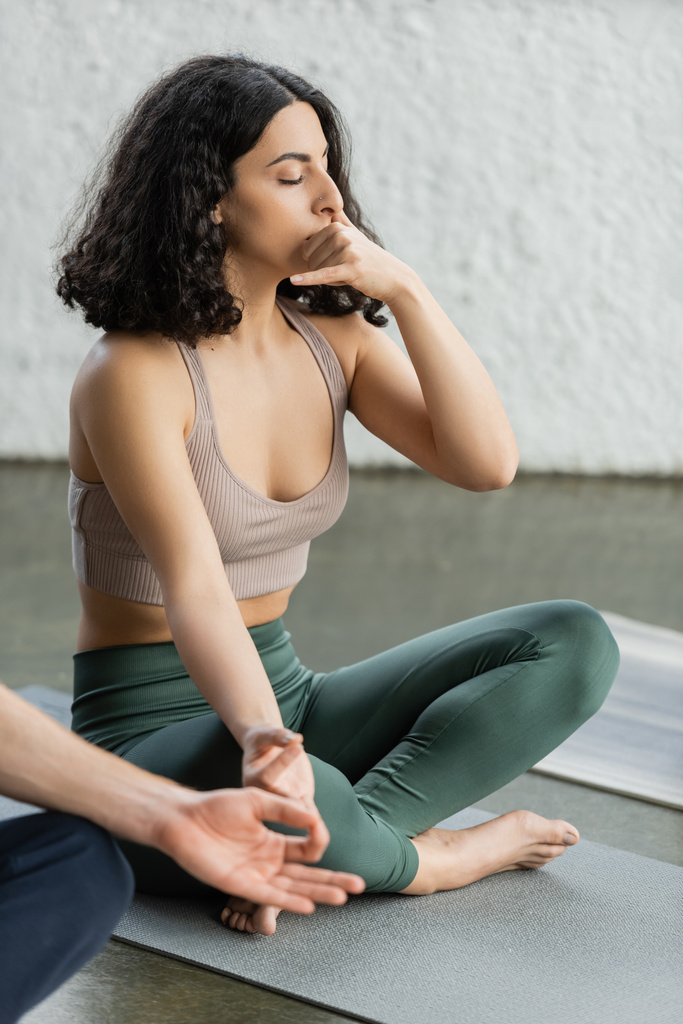 Femme du Moyen-Orient en vêtements de sport pratiquant mudra gyan et respiration narine en studio de yoga  - Photo, image