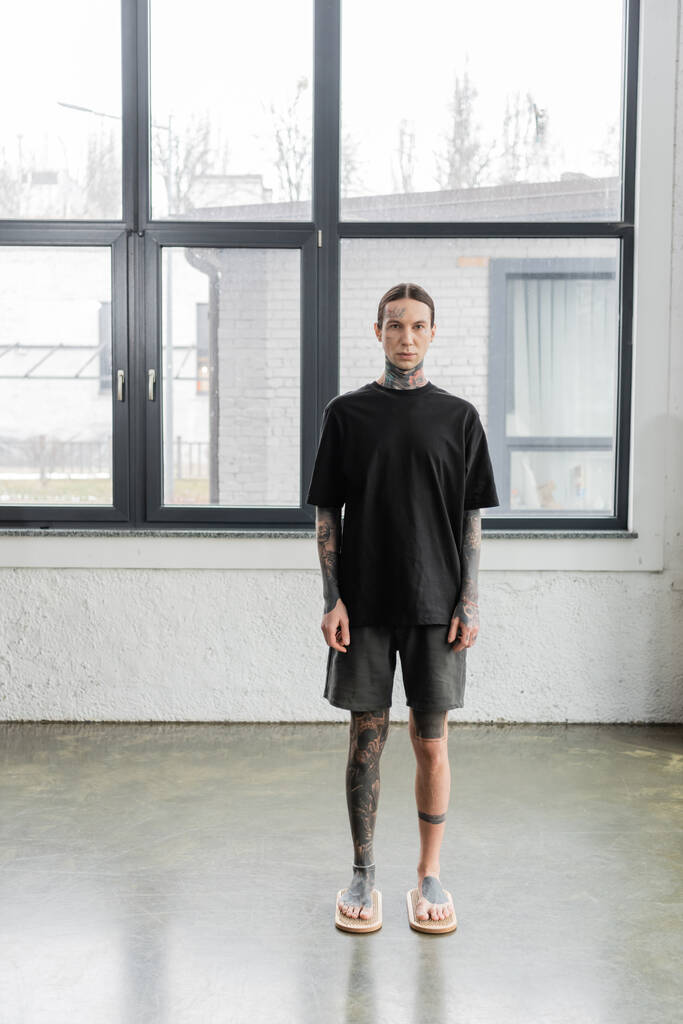 mezítlábas férfi tetovált lábakkal szadhu körömdeszkán áll jóga stúdióban  - Fotó, kép