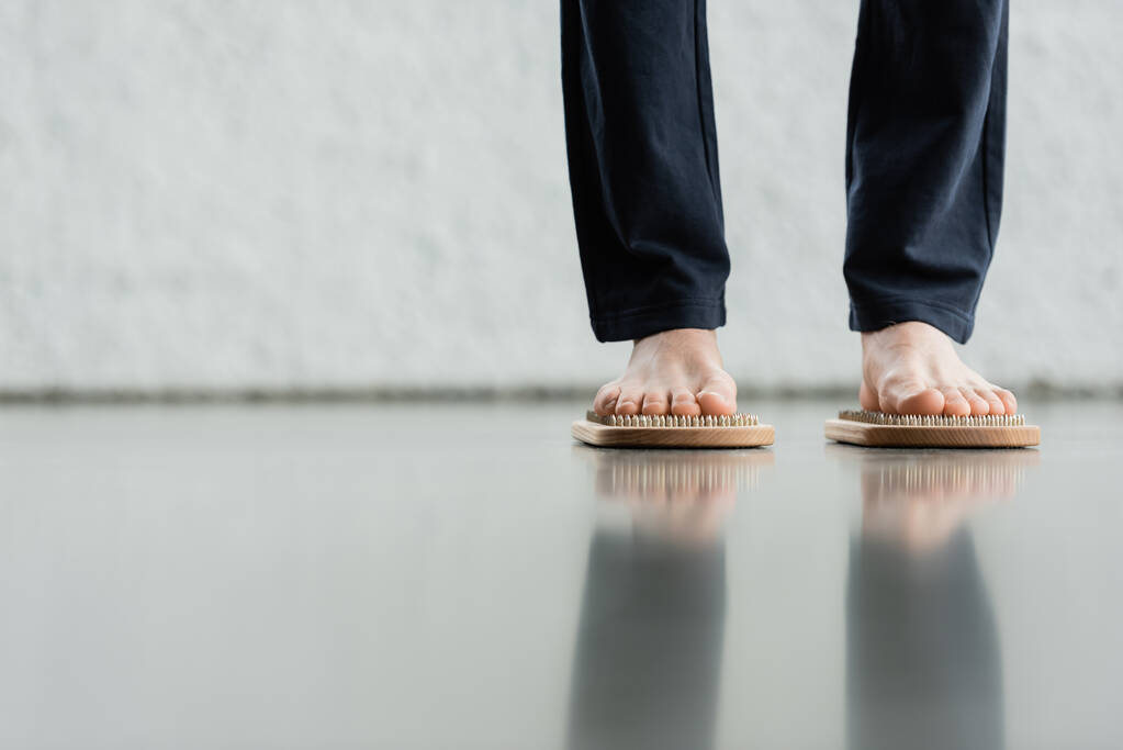обрезанный вид человека в штанах, стоящего на доске для ногтей Садху в студии йоги  - Фото, изображение