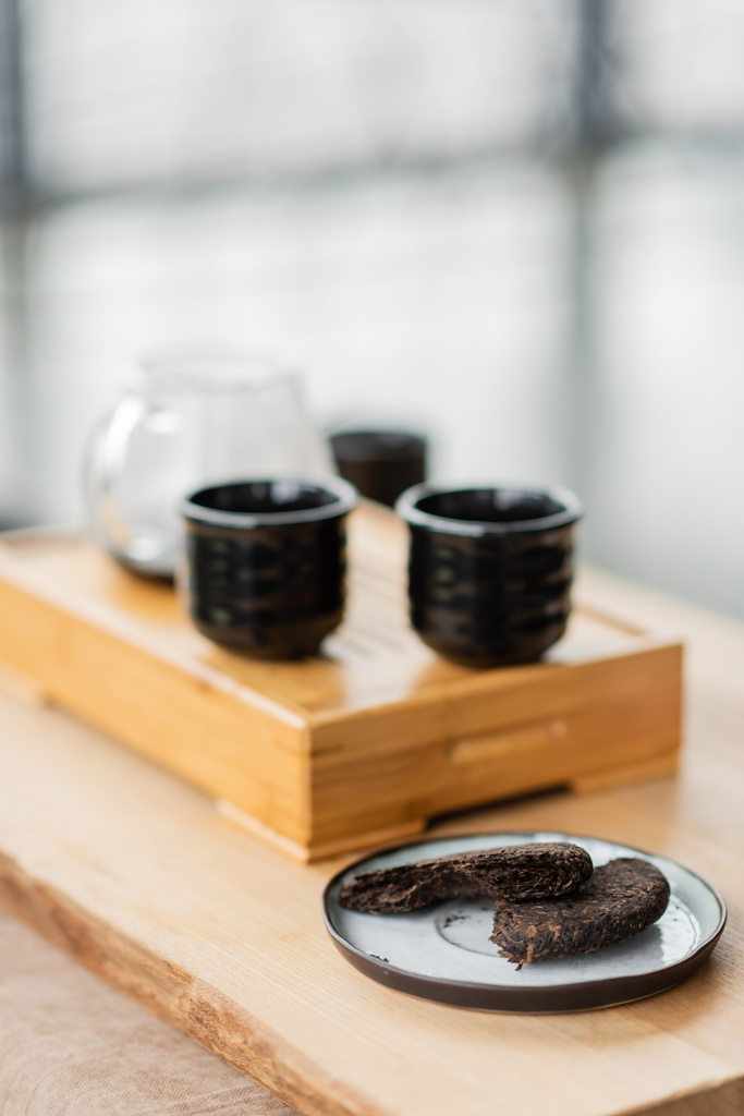 Yoga stüdyosunda Japon çay fincanlarının yanındaki tabakta sıkıştırılmış pu-erh çayı.  - Fotoğraf, Görsel
