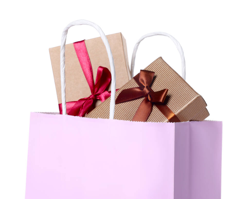 Rosa Papiereinkaufstasche voller Geschenkboxen auf weißem Hintergrund - Foto, Bild