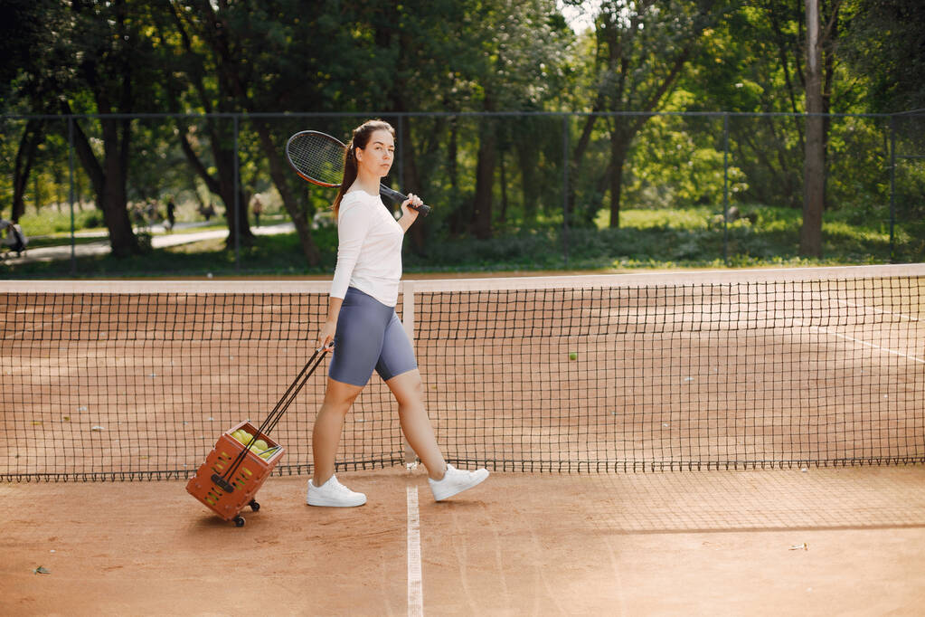 テニスの選手はテニスのカートを通って行く。モデルポーズ。趣味スポーツ用具. - 写真・画像