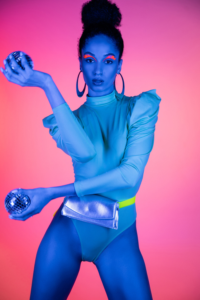 Muodikas afrikkalainen amerikkalainen malli neon meikki ja kehonpuku tilalla disco pallot vaaleanpunainen tausta - Valokuva, kuva