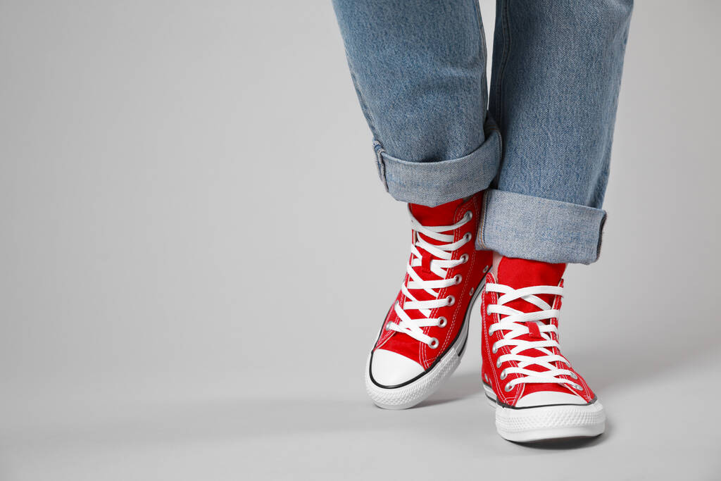 Γυναίκα που φοράει καινούρια stylish sneakers σε ανοιχτό γκρι φόντο, κοντινό πλάνο. Χώρος για κείμενο - Φωτογραφία, εικόνα