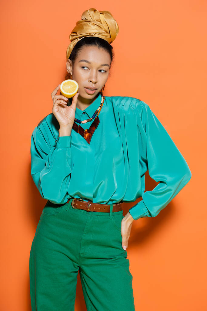 Trendy african - африканская женщина, держащая лемон и позирующая на оранжевом фоне  - Фото, изображение
