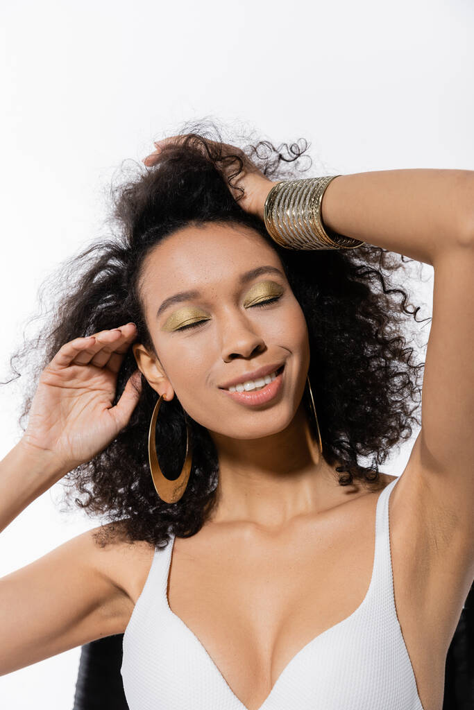 modello afroamericano ad occhi chiusi che regola i capelli ricci isolati su bianco  - Foto, immagini